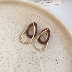 Détail des boucles d'oreilles rétro en bois foncé et or avec design de goutte d'eau
