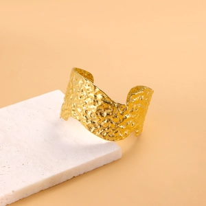 Chic gold-plated open bangle with irregular hammered texture on stone display