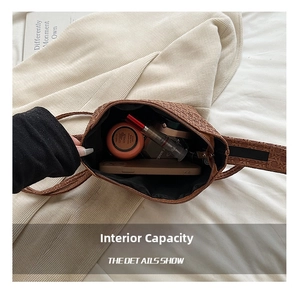 Detail showing the spacious interior of the brown woven crossbody bag with daily essentials