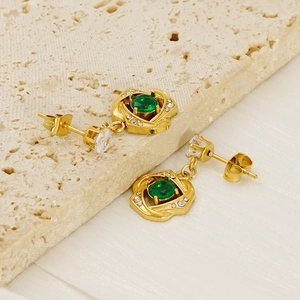 Detail of gold titanium steel earrings with green oval gemstone and hollow zircon patterns