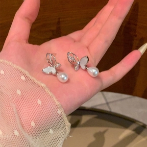 Detailed view of silver butterfly earrings with shell inlay and teardrop pearls