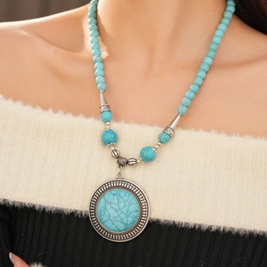 Close-up of bohemian turquoise beaded necklace with large round vintage silver pendant