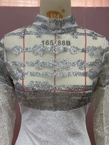 Detail of white sequin dress showing intricate wave patterns on sheer mesh fabric