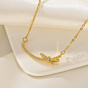 Close-up of gold butterfly bow necklace with sparkling zircon pavé on a smooth silk background