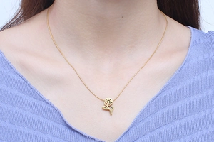 Close-up of a gold stainless steel rose flower necklace on a female model neck