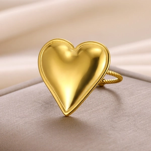 Close-up of golden heart ring with twisted band texture on brown leather surface