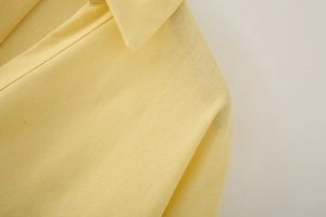 Close-up of vibrant yellow linen shirt detailing the V-neckline and fine fabric texture