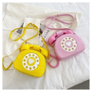 Detail view of yellow and pink creative telephone crossbody bag with heart dial design