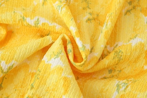 Macro shot of yellow floral fabric with crinkled texture and sweet summer flower print
