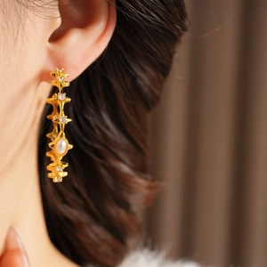 Close-up of vintage gold starburst earrings with white pearls and zircon accents