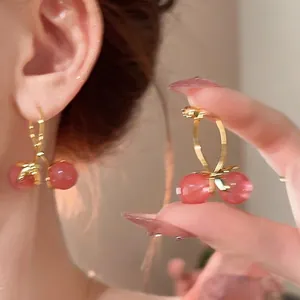 Detail of pink cherry earrings with glass beads and gold leaves on a sweet floral design