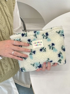 Floral plush makeup bag in beige fleece with blue flower patterns and woven label