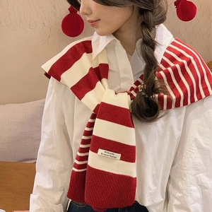 Close-up of red and white striped knitted shawl with a premium logo patch on the shoulder