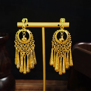 Detail of bohemian gold drop tassel earrings with hollow rings on a black display