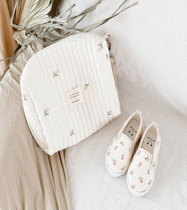 Detailed view of beige quilted cotton diaper bag and kids shoes with tulip embroidery