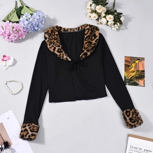 Dettaglio di cardigan in maglia nera con bordi in finta pelliccia leopardata