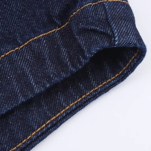Gros plan sur le denim bleu foncé avec des coutures contrastées jaunes et texture fine