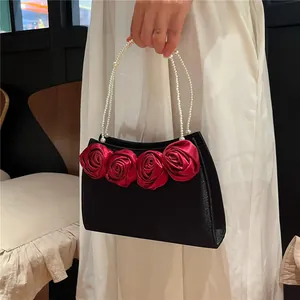 Macro shot of red satin roses and white pearl bead handle on vintage black handbag