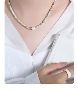 Detail of beaded necklace with freshwater pearls and a gold-edged white enamel ring