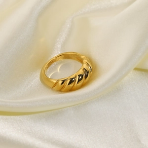Detail of 18K gold-plated croissant ring on elegant beige silk fabric background