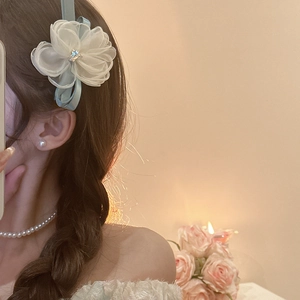 Detail of white organza flower hair clip with rhinestones and light blue ribbon silk