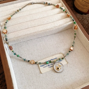 Détail d'un collier de perles avec pendentif soleil lune dans une boîte à bijoux en bois