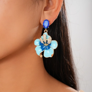 Detail view of blue enamel floral earring with rhinestones worn on a model ear