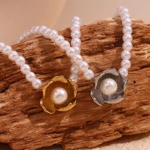 Detailed view of flower pendants in gold and silver finish on pearl necklaces