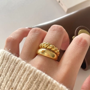Close-up of a stacked gold dome ring and croissant twisted band on a model's finger