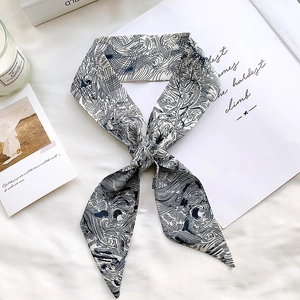 Detail showing elegant blue and white swirl pattern twilly silk scarf tied in a bow