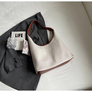 Sac hobo blanc cassé à texture litchi avec bandoulières marron sur fond de tissu blanc