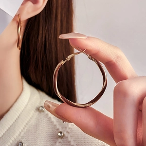 Detailed view of model wearing a golden twisted hoop earring with polished metallic texture