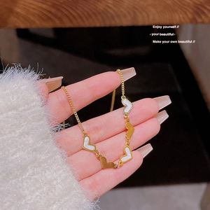 Detail view of a gold heart necklace featuring multiple white heart-shaped charms