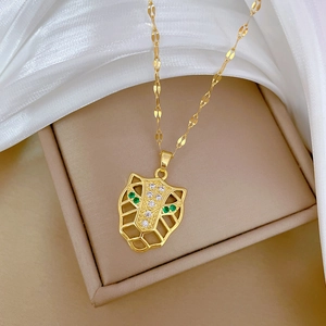Detailed close-up of a gold leopard head pendant with green zircon eyes and white crystals