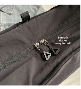 Detail view of smooth double zippers and tear-resistant nylon fabric on black crossbody bag