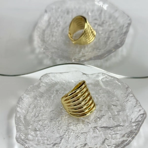 Close-up detail of 18k gold plated multi-layer spiral ring on textured glass