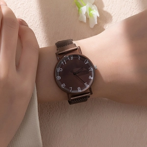 Close-up of brown Milanese strap watch with hand-drawn numeral dial on beige floral surface