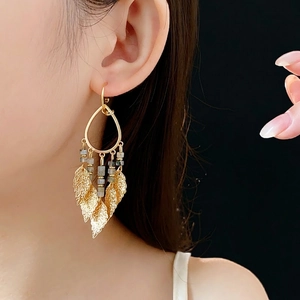 Elegant gold leaf drop earrings with grey stone tassels shown on model against black backdrop