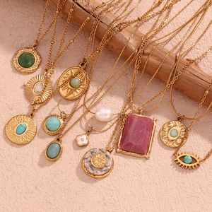 Detail of 18K gold plated necklaces with turquoise, pearls and evil eye on wooden branch