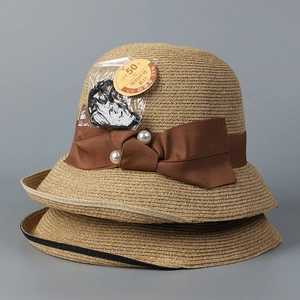 Close-up of woven straw hat featuring a bow with pearls and UPF 50+ UV protection tag