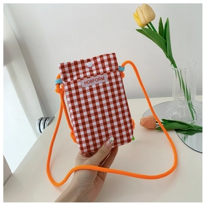 Close-up of a red and white checkered crossbody phone bag with orange rope strap in a modern aesthetic