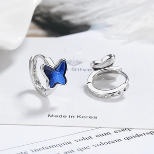 Silver hoop earrings featuring deep blue butterfly pendants on white jewelry card