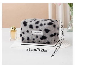 Detail view of plush cow print makeup bag with size dimensions 21x14x9 cm and logo label