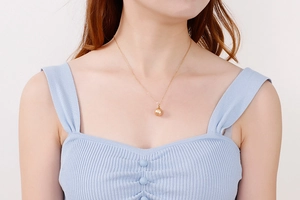Gros plan d'un collier doré élégant avec pendentif perle de nacre sur un mannequin