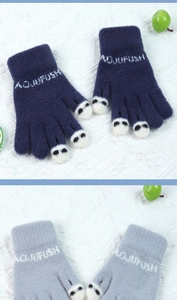 Detail of knitted winter gloves featuring cute panda faces in navy and grey colors