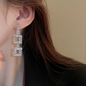 Detail of silver geometric square earrings with sparkling crystals on model