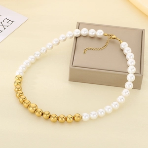 French vintage titanium steel necklace with white pearls and gold beads on a beige jewelry box