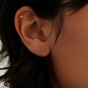 Detail of gold-plated silver cartilage stud with star shape and central diamond on ear