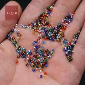 Close-up of mixed 2mm silver-lined glass seed beads held in hand for size comparison