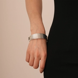 Close-up of wide multi-layer silver leopard texture bangle worn on wrist over black sleeve